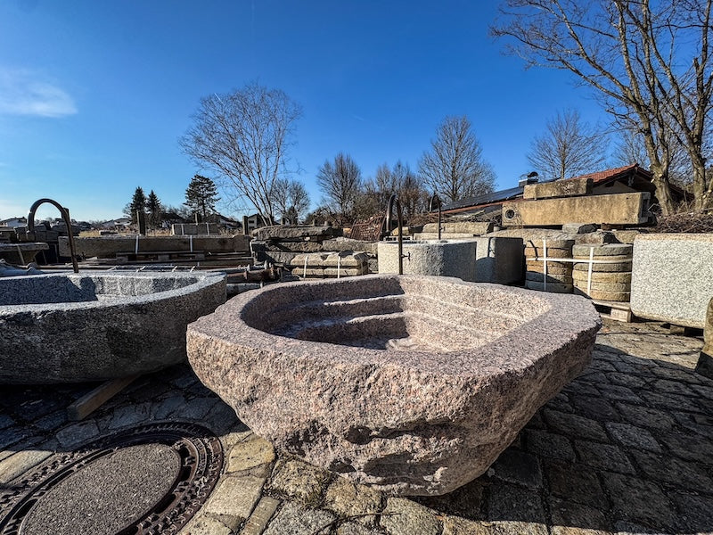 Findlingsbrunnen mit dunklen und rosa Einschlüssen