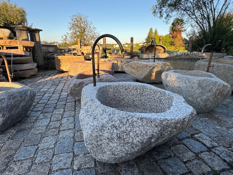 Findlingsbrunnen grau mit dunklen Einschlüssen