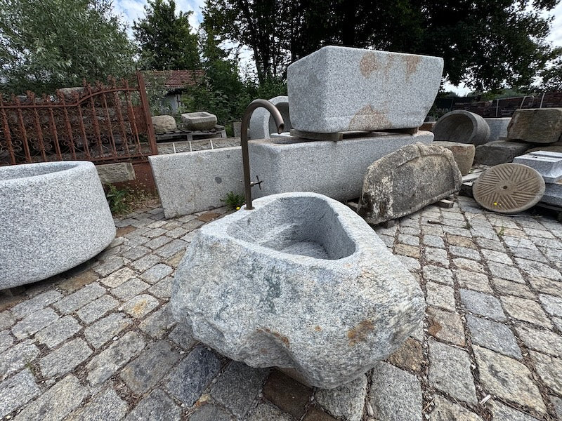 Findlingsbrunnen grau mit dunklen Einschlüssen
