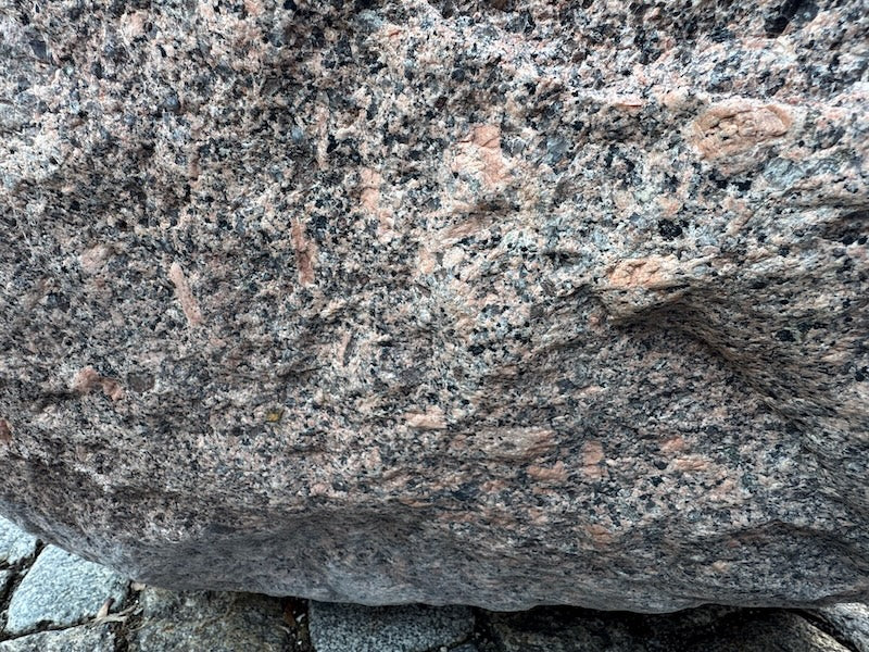 Findlingsbrunnen mit dunklen und rosa Einschlüssen