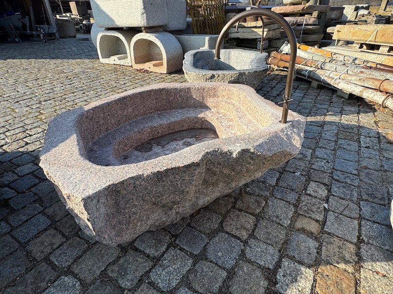 Findlingsbrunnen mit dunklen und rosa Einschlüssen