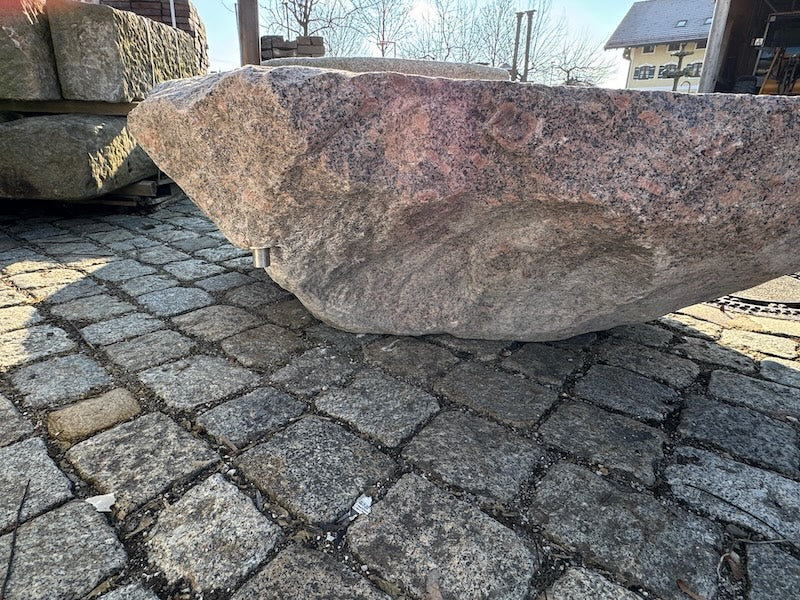 Findlingsbrunnen mit dunklen und rosa Einschlüssen