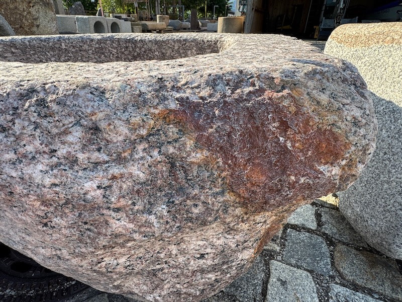 Gartenbrunnen mit Wasserhahn und roten Einschlüssen