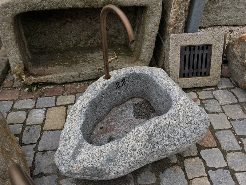 Kleiner Findlingsbrunnen mit farblichen Einschlüssen.