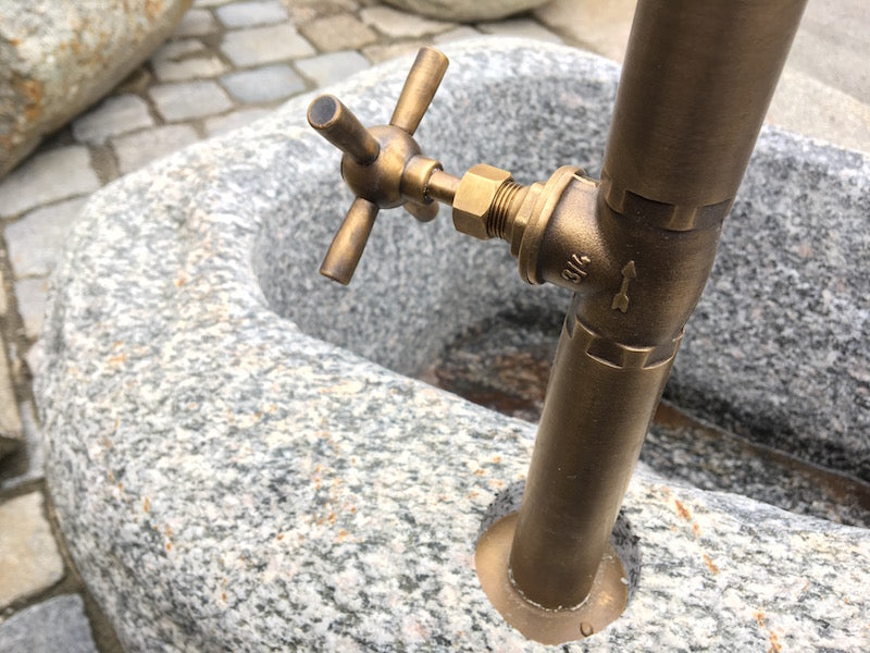 Kleiner Findlingsbrunnen mit farblichen Einschlüssen Handrad