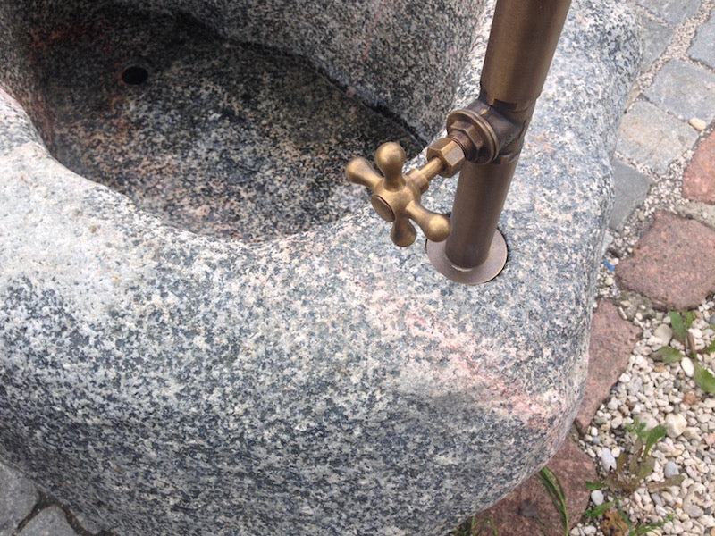 Findlingsbrunnen mit roten Adern und Handrad