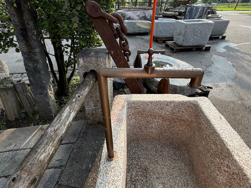Steinbrunnen mit Naturoberfläche und Wasserauslauf