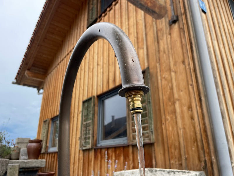 Findlingsbrunnen aus grauem Granit mit Messingeinlauf