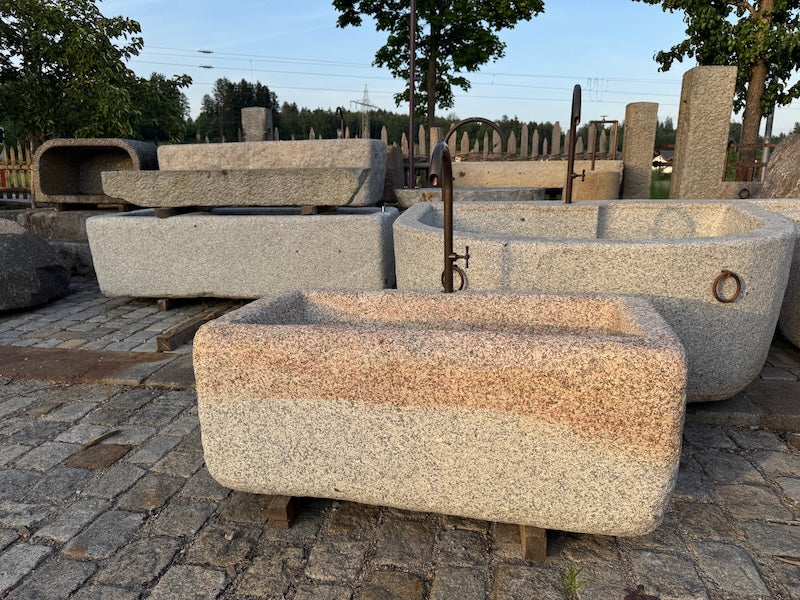 Steinbrunnen aus grauem Granit mit Wasserhahn