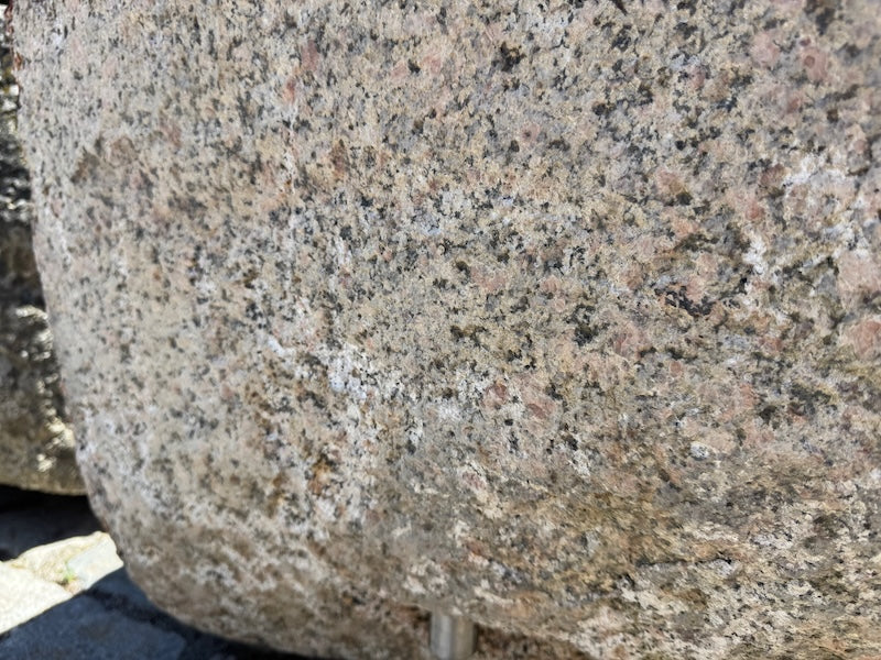 Findlingsbrunnen mit dunklen und rosa Einschlüssen