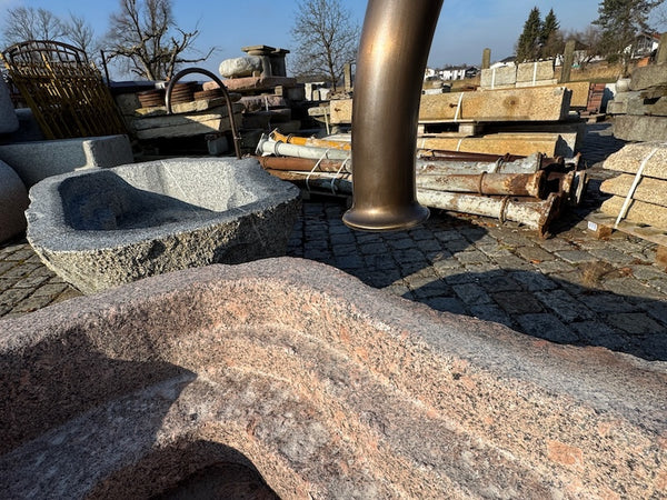 Findlingsbrunnen mit dunklen und rosa Einschlüssen