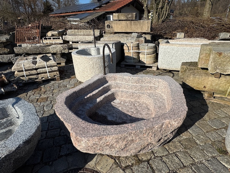 Findlingsbrunnen mit dunklen und rosa Einschlüssen