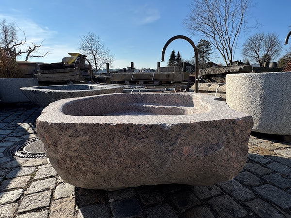 Findlingsbrunnen mit dunklen und rosa Einschlüssen