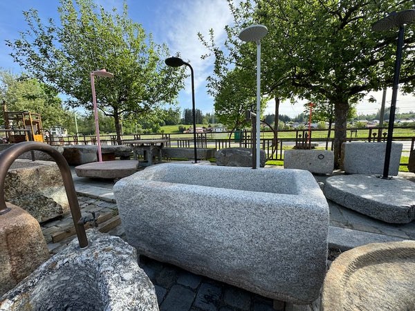 Steinbrunnen aus grauem Granit mit Wasserhahn