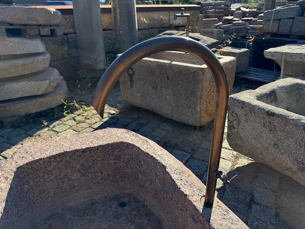 Großer roter Findlingsbrunnen mit Messingwassereinlauf