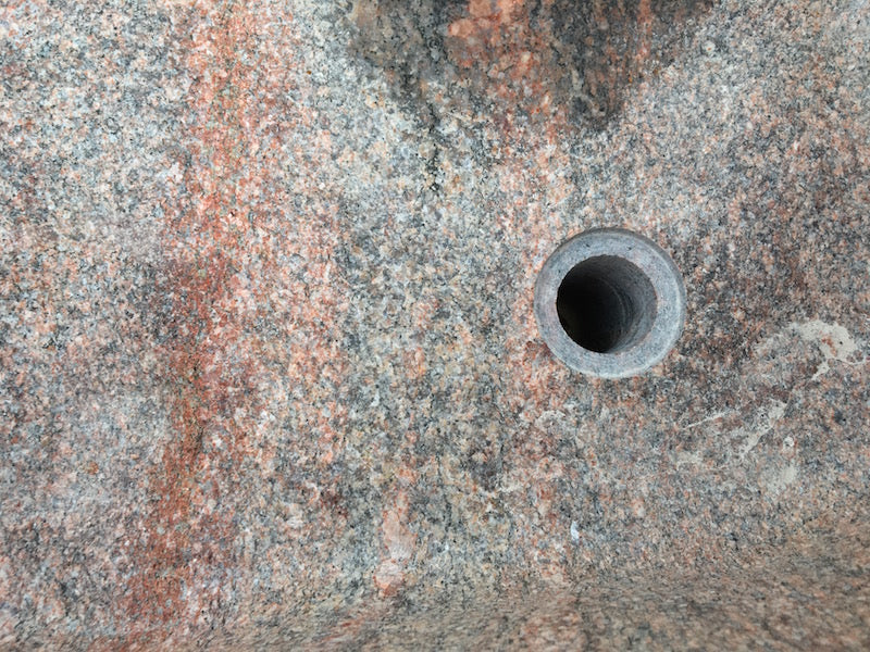 Findlingsbrunnen in rosa mit schwarzen Schlieren